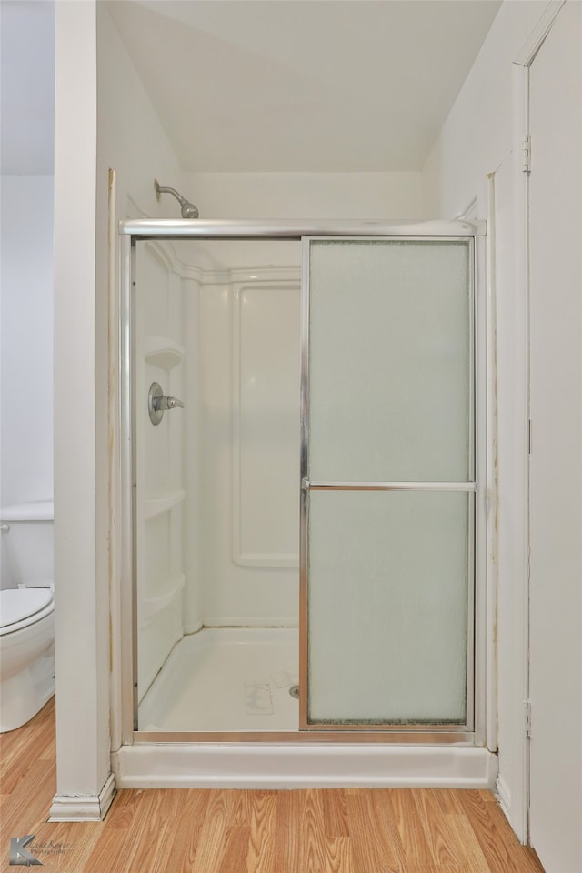 bathroom featuring hardwood / wood-style floors, an enclosed shower, and toilet