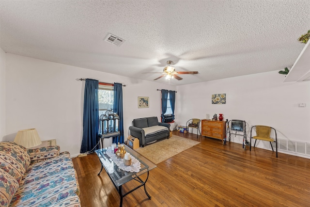 living room featuring a textured ceiling, ceiling fan, and dark wood-type flooring