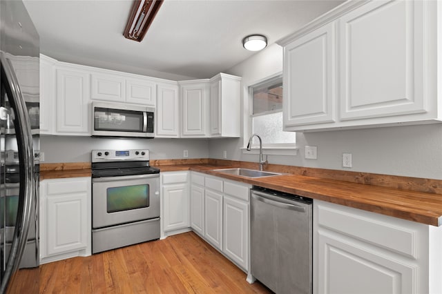 kitchen with butcher block counters, white cabinetry, sink, appliances with stainless steel finishes, and light wood-type flooring