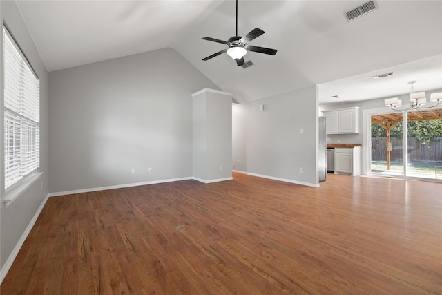 unfurnished living room featuring lofted ceiling, wood-type flooring, and ceiling fan with notable chandelier