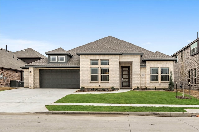 prairie-style home with brick siding, driveway, an attached garage, and a front yard