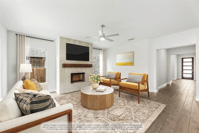 living room with a tiled fireplace, ceiling fan, and hardwood / wood-style floors