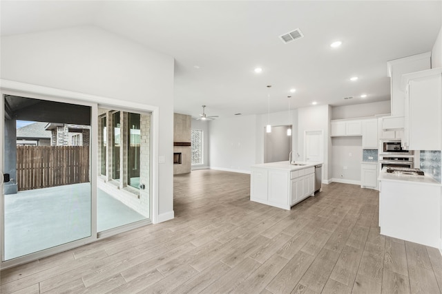 kitchen featuring white cabinetry, sink, ceiling fan, an island with sink, and light wood-type flooring