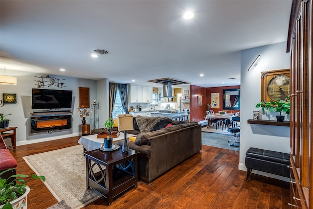 living room with an AC wall unit and dark wood-type flooring