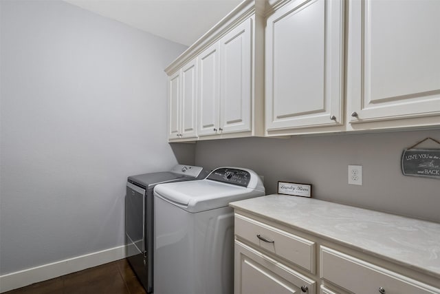 clothes washing area featuring washing machine and dryer, cabinet space, and baseboards