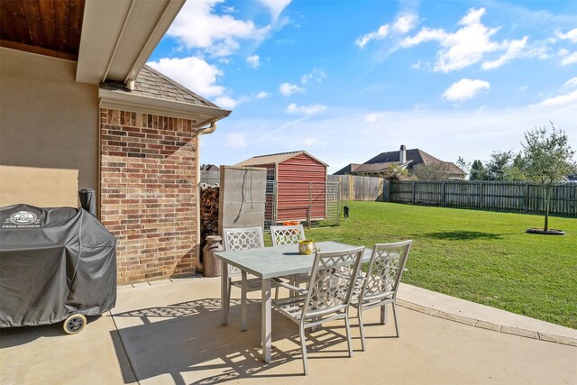 view of patio / terrace featuring a storage shed, a fenced backyard, grilling area, an outbuilding, and outdoor dining space