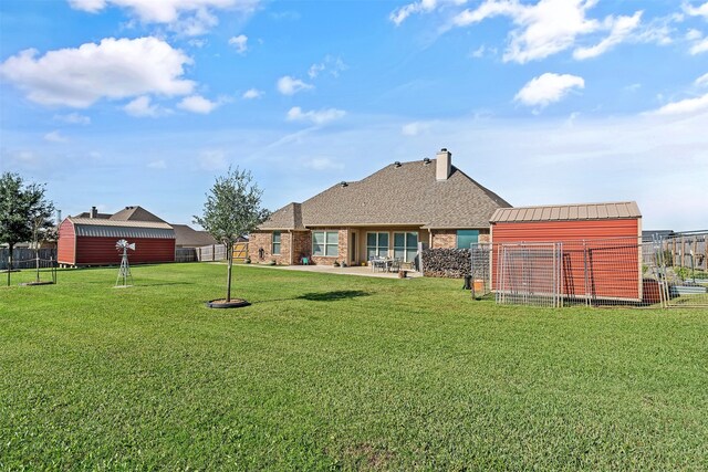 back of house with a yard, fence, and an outbuilding