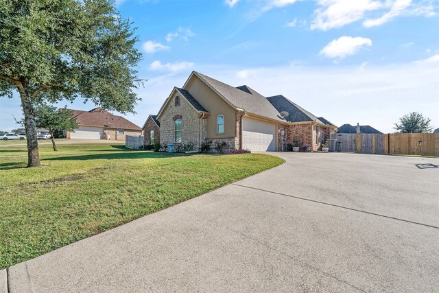 view of front of property with concrete driveway, an attached garage, fence, a front yard, and brick siding