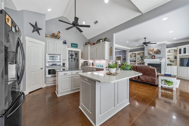 kitchen with stainless steel appliances, a peninsula, dark tile patterned floors, a fireplace, and visible vents