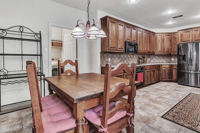 kitchen with decorative light fixtures, stainless steel fridge, decorative backsplash, and a chandelier