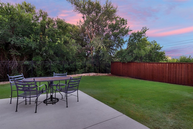 patio terrace at dusk featuring a yard