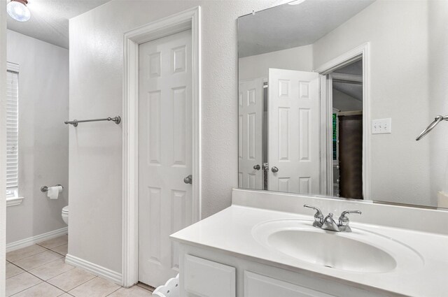 bathroom with tile patterned flooring, a textured ceiling, vanity, and toilet