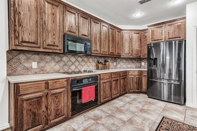 kitchen with a textured ceiling, tasteful backsplash, and black appliances