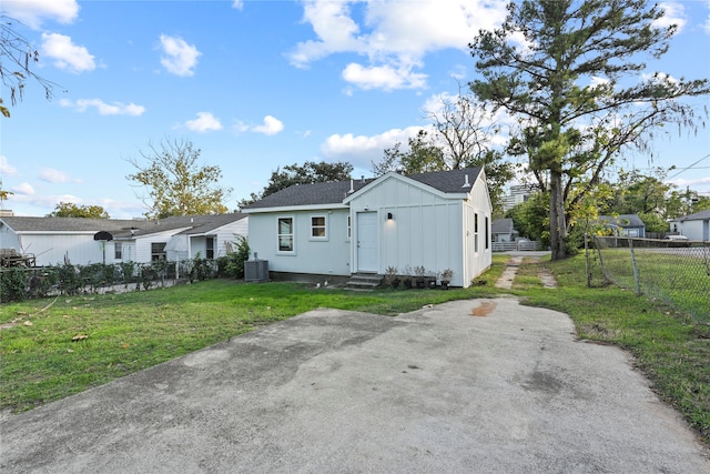 rear view of house featuring central AC unit, fence, a yard, entry steps, and board and batten siding