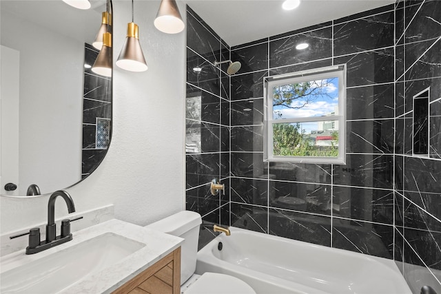 full bathroom featuring vanity, tiled shower / bath combo, and toilet