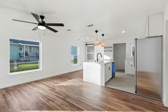 kitchen with a center island with sink, stainless steel fridge, light hardwood / wood-style floors, and pendant lighting