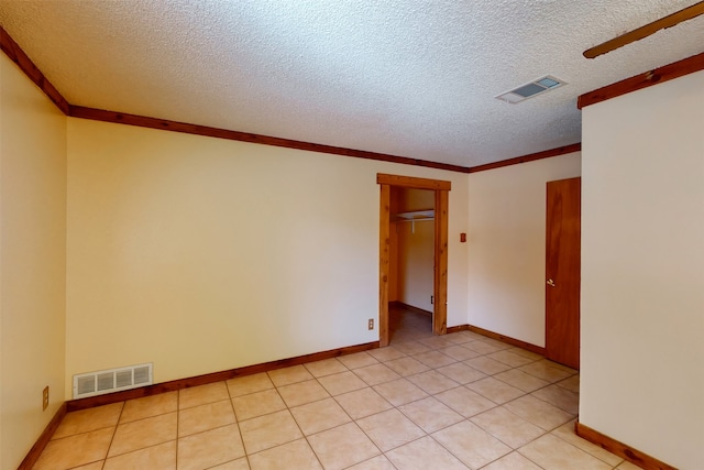 empty room with ceiling fan, light tile patterned flooring, crown molding, and a textured ceiling