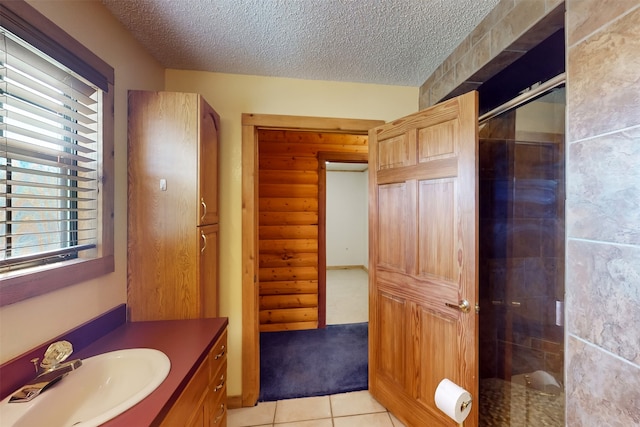 bathroom with tile patterned floors, plenty of natural light, a shower with shower door, and a textured ceiling