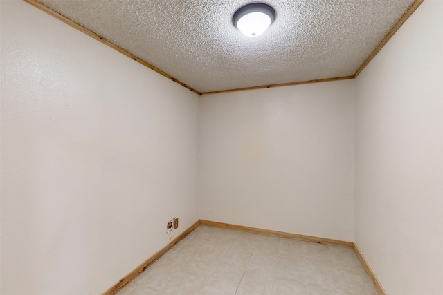 empty room with ornamental molding and a textured ceiling