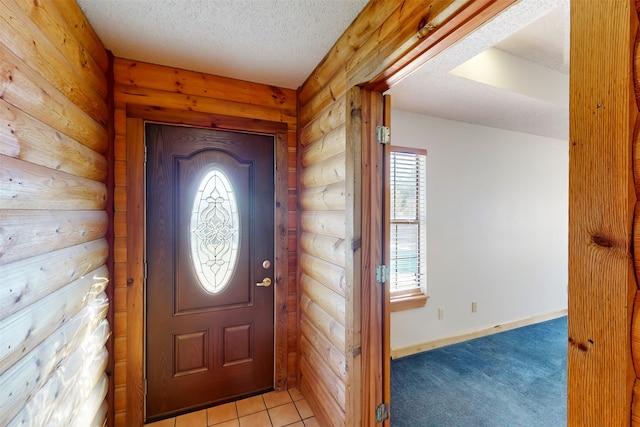 entrance foyer with light tile patterned floors, a textured ceiling, and rustic walls