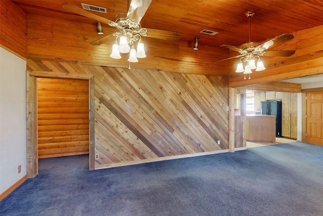 unfurnished living room featuring dark colored carpet, wooden ceiling, ceiling fan, and wooden walls