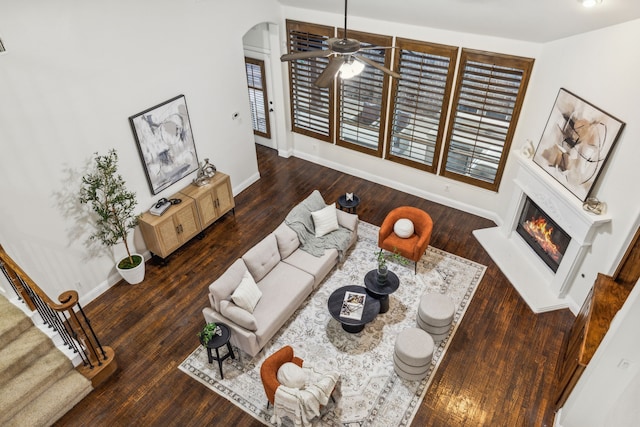 living room with dark hardwood / wood-style floors, ceiling fan, and a towering ceiling