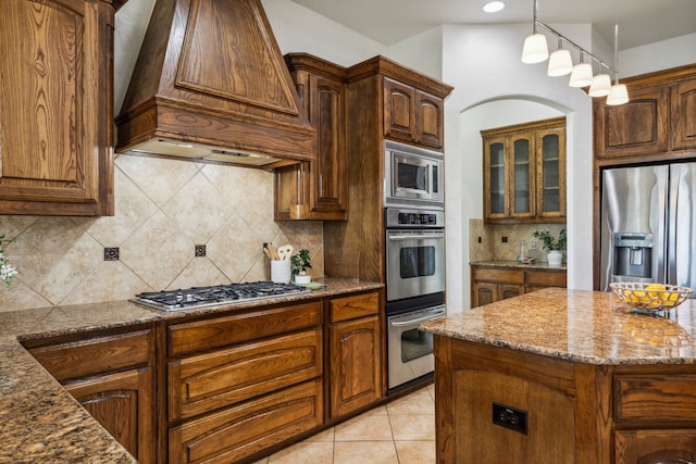 kitchen with a center island, stainless steel appliances, dark stone countertops, decorative backsplash, and custom range hood