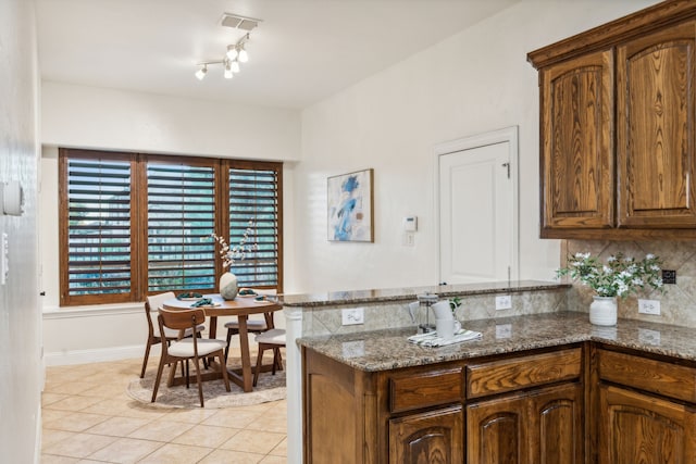 kitchen featuring dark stone countertops, light tile patterned floors, and tasteful backsplash