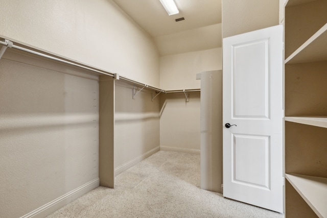 walk in closet featuring light colored carpet and lofted ceiling