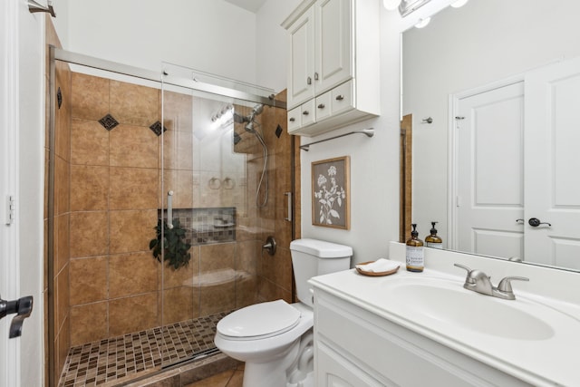 bathroom with tile patterned floors, vanity, toilet, and a shower with shower door