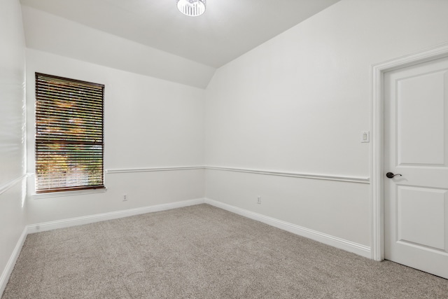 carpeted spare room featuring vaulted ceiling