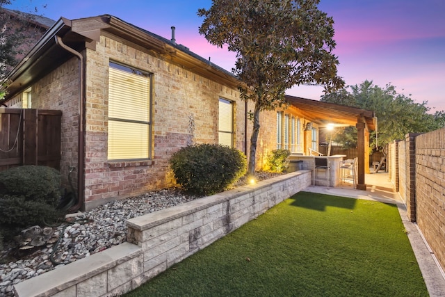 property exterior at dusk featuring a yard