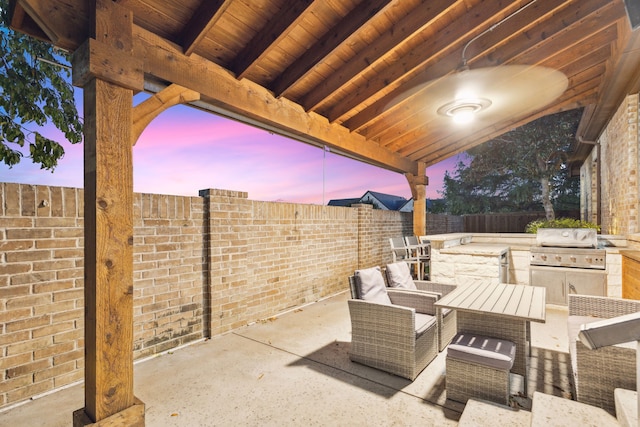 patio terrace at dusk featuring area for grilling and a grill