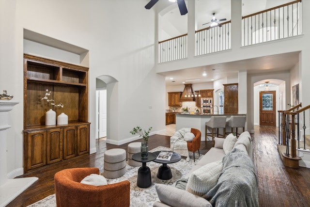 living room with ceiling fan, dark hardwood / wood-style flooring, a high ceiling, and sink