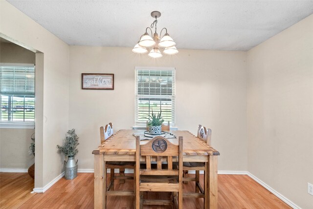 dining area with a textured ceiling, light hardwood / wood-style flooring, and a notable chandelier