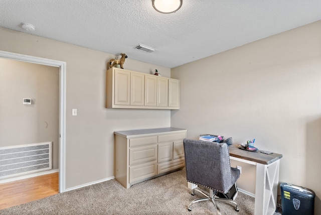 office area with a textured ceiling and light carpet