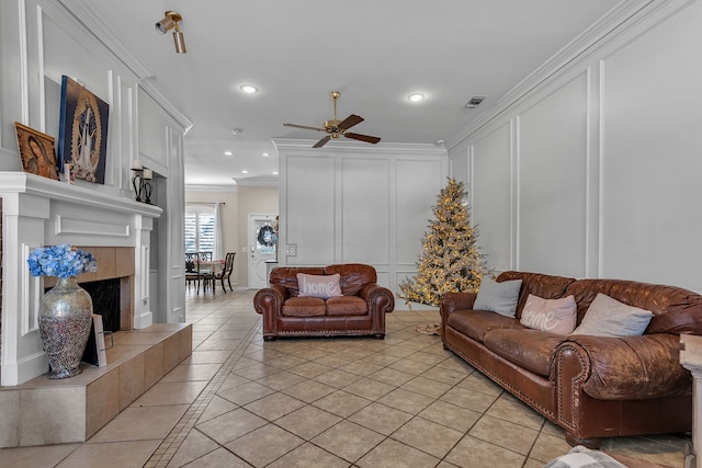 living room with crown molding, light tile patterned floors, ceiling fan, and a fireplace