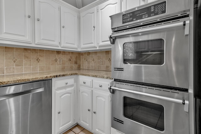 kitchen featuring white cabinetry, light stone counters, tasteful backsplash, and appliances with stainless steel finishes