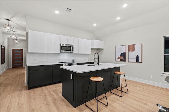 kitchen featuring stainless steel appliances, a kitchen island with sink, sink, white cabinets, and light hardwood / wood-style floors