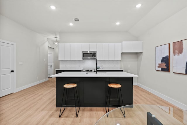 kitchen with white cabinets, a kitchen island with sink, and light hardwood / wood-style flooring