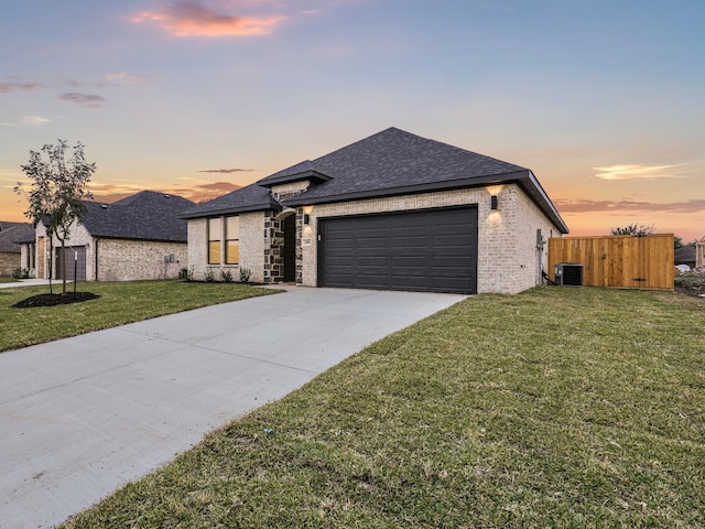 view of front of house featuring central AC, a garage, and a lawn