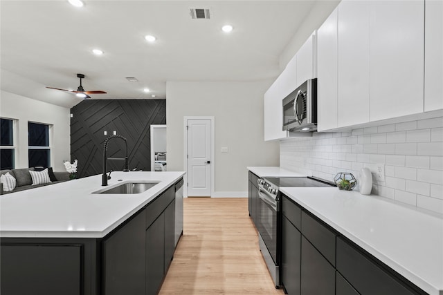 kitchen featuring white cabinetry, sink, stainless steel appliances, and a center island with sink