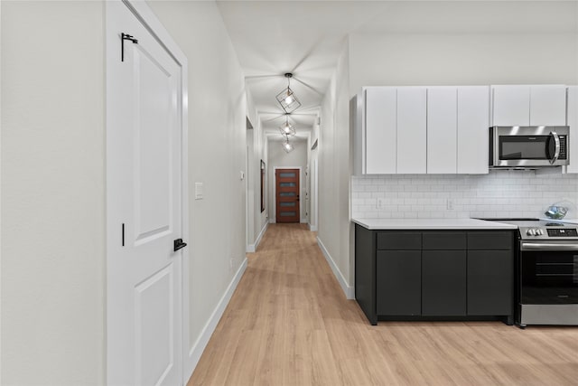 kitchen featuring white cabinets, light wood-type flooring, stainless steel appliances, and tasteful backsplash