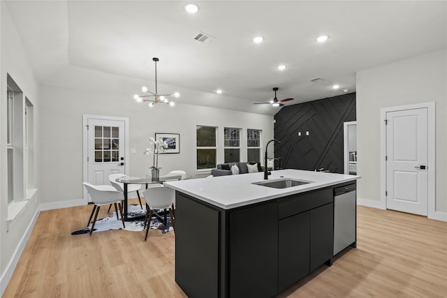 kitchen featuring sink, stainless steel dishwasher, a kitchen island with sink, ceiling fan with notable chandelier, and light wood-type flooring