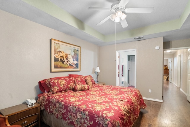 bedroom with hardwood / wood-style flooring, ceiling fan, and a raised ceiling