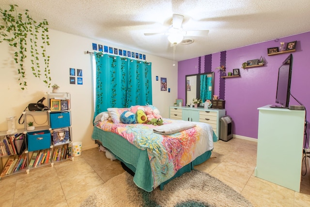 bedroom featuring ceiling fan, light tile patterned floors, and a textured ceiling