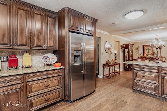 kitchen with light stone countertops, crown molding, light hardwood / wood-style flooring, a notable chandelier, and stainless steel fridge with ice dispenser