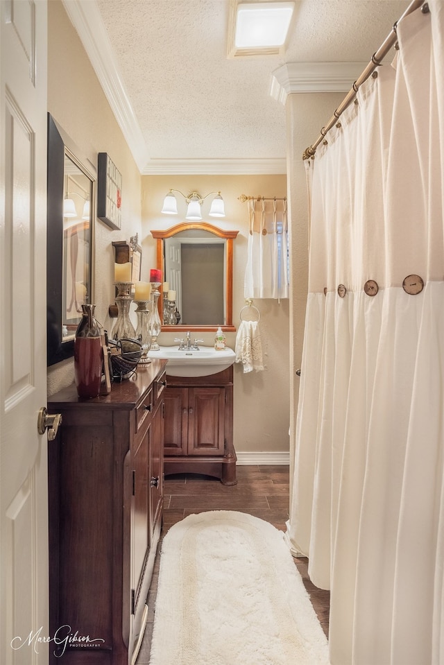 bathroom featuring hardwood / wood-style flooring, vanity, ornamental molding, and a textured ceiling