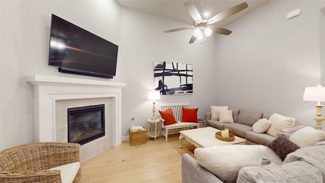 living room featuring a fireplace, light hardwood / wood-style floors, high vaulted ceiling, and ceiling fan