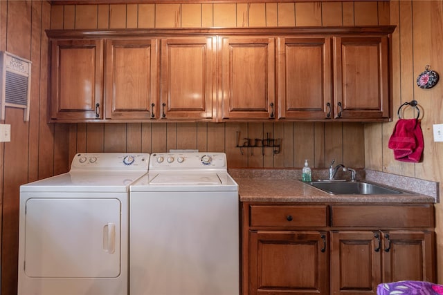 laundry area featuring cabinets, washer and clothes dryer, sink, and wood walls